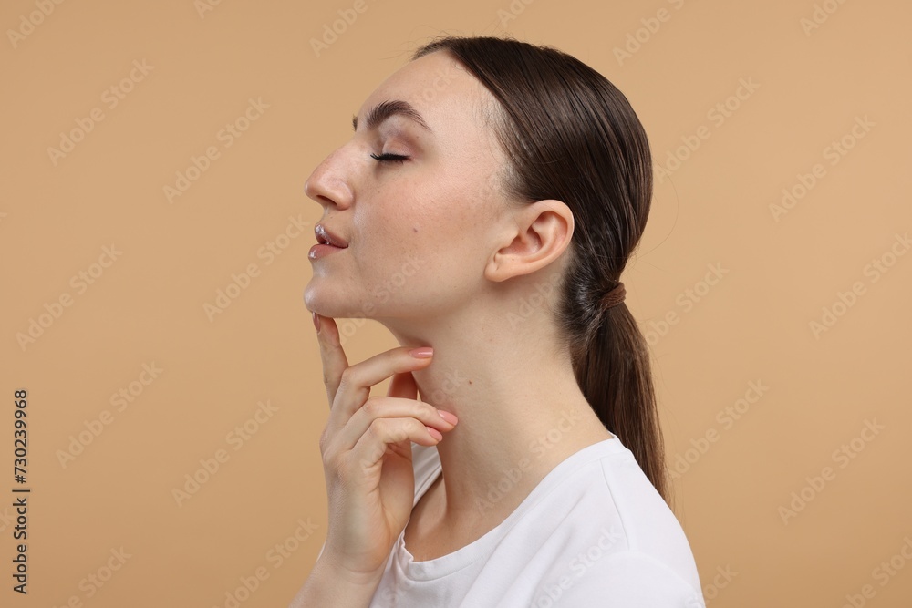Beautiful woman touching her chin on beige background Beautiful woman touching her chin on beige background