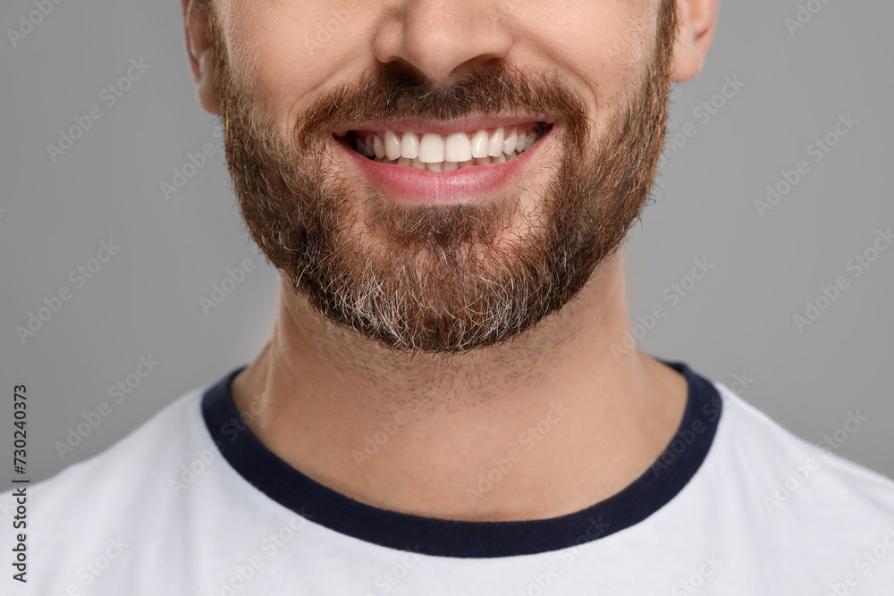 Smiling man with healthy clean teeth on grey background, closeup