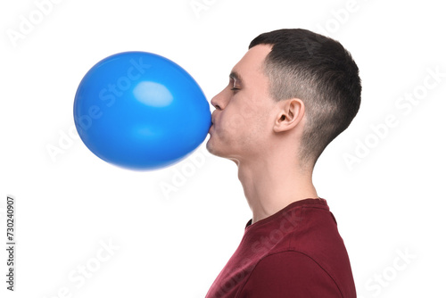 Young man inflating light blue balloon on white background