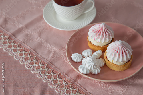 white and pink cupcakes  and cup of tea on vintage tablecloth