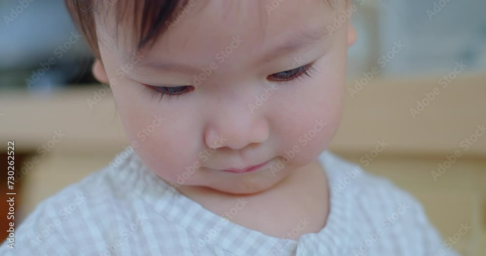 Intimate close-up of a pensive toddler with eyes cast down, in a soft-focus indoor environment. Intimate close-up of a pensive toddler with eyes cast down, in a soft-focus indoor environment.