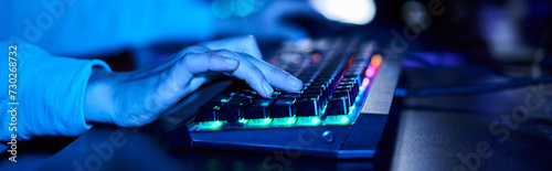 banner of cropped female hands typing on computer keyboard with illumination, blue light photo