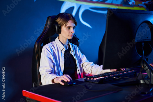 focused gamer with short hair looking at computer in a blue-lit room, cybersport player © LIGHTFIELD STUDIOS