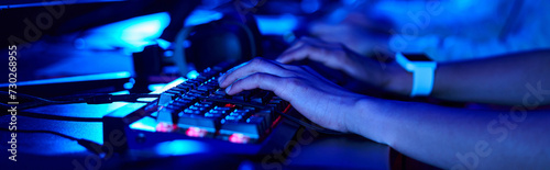cropped banner of female hands, young gamer using computer keyboard while playing game, cybersport photo