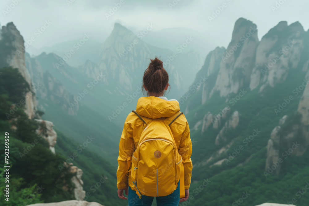 a woman in a yellow backpack looks out at the chinese mountains. Background image. Created with Generative AI technology