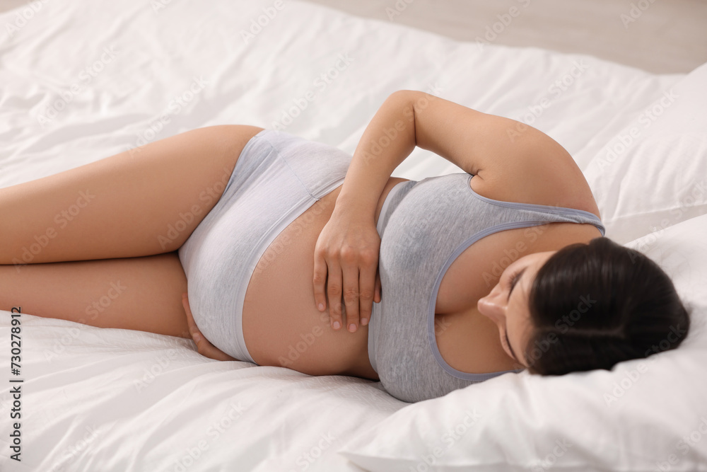 Obraz premium Beautiful pregnant woman in comfortable maternity underwear lying on bed
