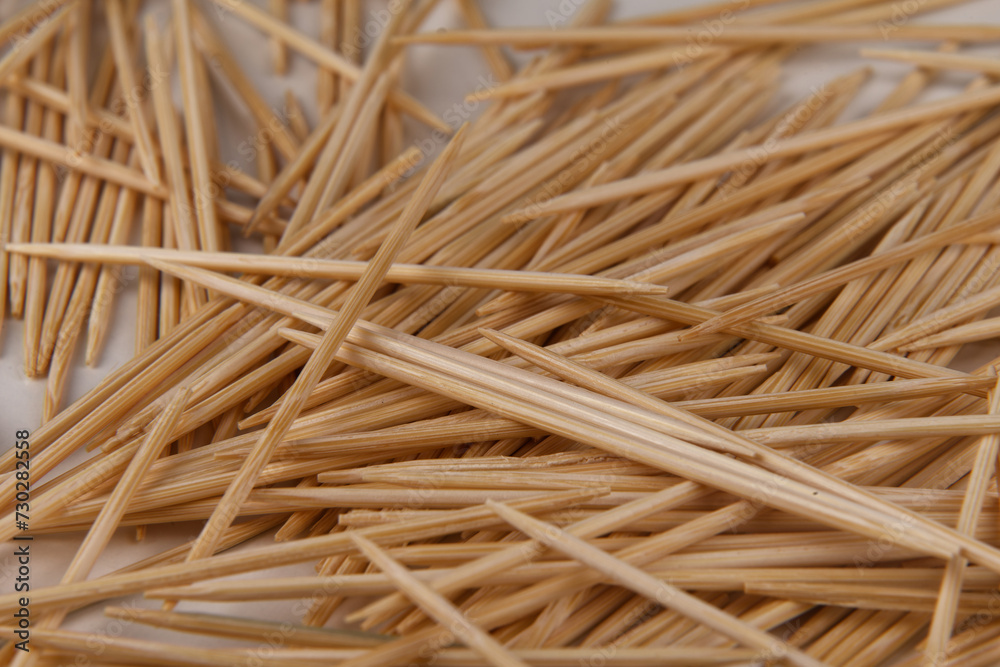 Many small toothpicks or wooden skewers lie disorganized on a white table Many small toothpicks or wooden skewers lie disorganized on a white table