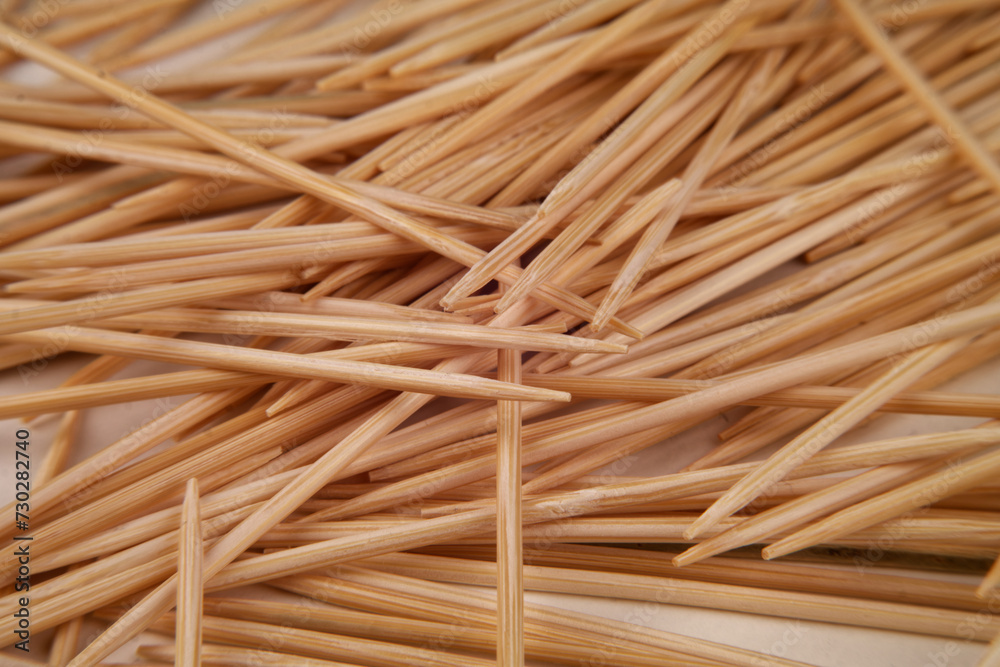 Many small toothpicks or wooden skewers lie disorganized on a white table Many small toothpicks or wooden skewers lie disorganized on a white table