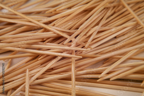 Many small toothpicks or wooden skewers lie disorganized on a white table