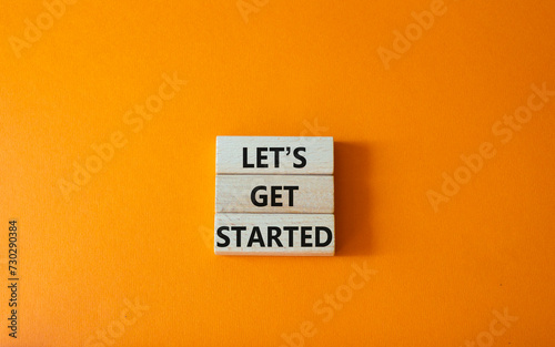 Lets get started symbol. Concept words Lets get started on wooden blocks. Beautiful orange background. Business and Lets get started concept. Copy space.