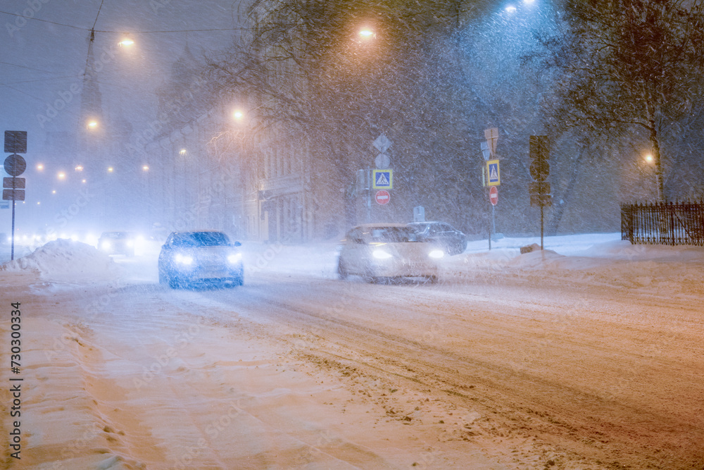 Φωτογραφία Cars driving along an evening winter city street during a snowstorm