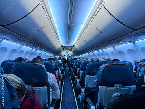 Fotografía An airplane cabin with beautiful lighting and passengers sitting with their back