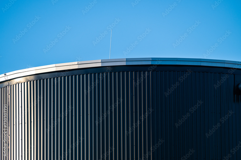 Top of a tall round grey metal tank. Top of a tall round grey metal tank.