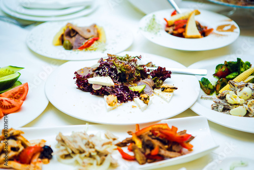 Various salads and meat on the white plates