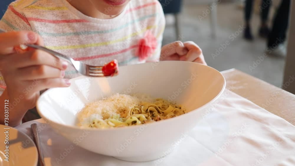 Hands of girl eating pasta from big plate in cafe, slow motion Hands of girl eating pasta from big plate in cafe, slow motion