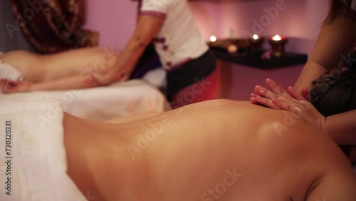 Hands of two masseurs doing massage for girl and man, slow motion photo