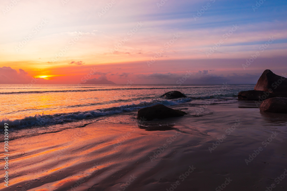 Seaside landscape with wet sand and coastal stones on the sunset