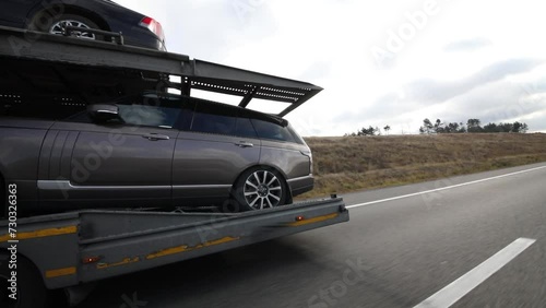 Large car carrier with cars moves on highway at autumn day