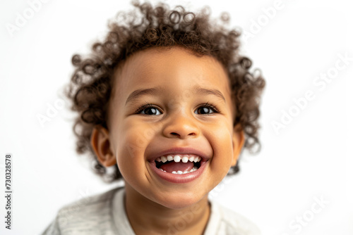 Joyful toddler with curly hair smiling on white background. Child happiness and innocence.