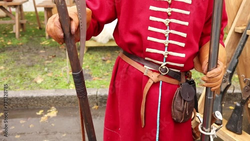 Close-up of man torso in uniform of russian sagittarius with an poleaxe and gun, slow motion photo
