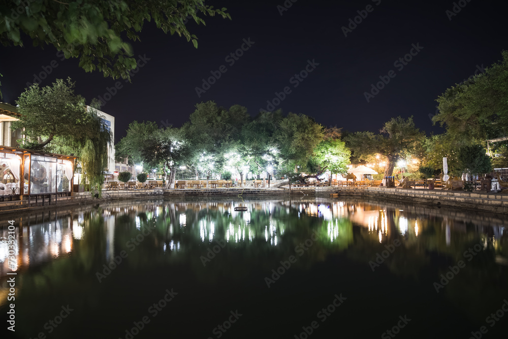 Evening view of Lyabi Khauz lake with reflection of the park and lanterns in the ancient city of Bukhara in Uzbekistan Evening view of Lyabi Khauz lake with reflection of the park and lanterns in the ancient city of Bukhara in Uzbekistan