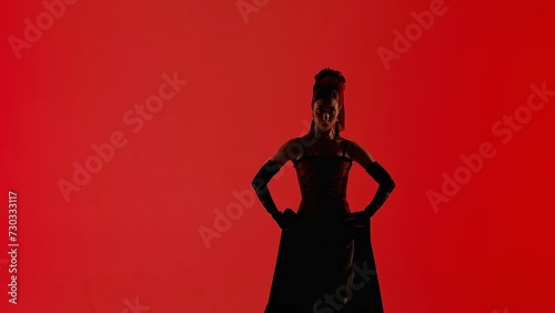 Woman dancer dancing on red background. Female in flamenco style dress performs elegant spanish dance moves with her hands and body in the studio.