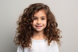 Portrait of a cute little girl with curly hair on grey background
