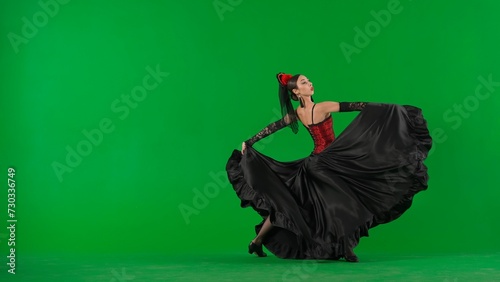 Woman dancer dancing on chroma key green screen. Female in flamenco style dress performs elegant spanish dance moves with her hands and body in the studio.