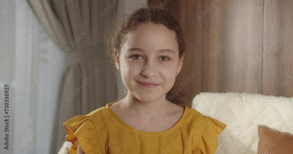 Portrait Funny little girl smiling child looking at camera are sitting on the couch at home, cute kid child with pretty face sitting on sofa. Concept of a happy childhood. 4K Portrait Funny little girl smiling child looking at camera are sitting on the couch at home, cute kid child with pretty face sitting on sofa. Concept of a happy childhood. 4K