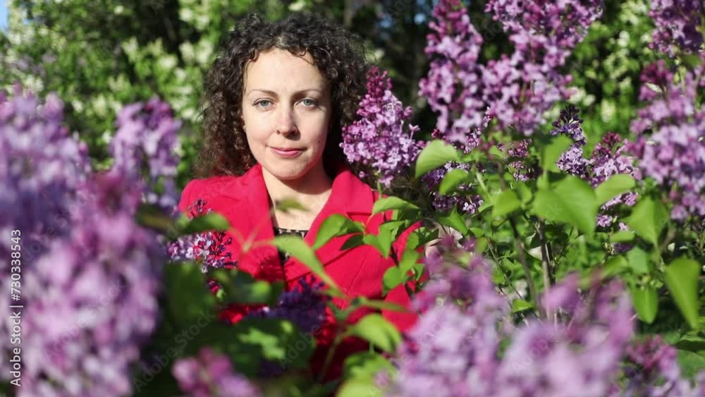 Happy woman stands among lilac flowers at sunny spring day, slow motion Happy woman stands among lilac flowers at sunny spring day, slow motion