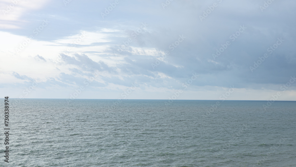wide sea As far as the eye can see, there is a horizontal line between the sea and the sky. Clearly demarcated The shadows of the clouds give the water a dark color. The surface is streaked in the sam