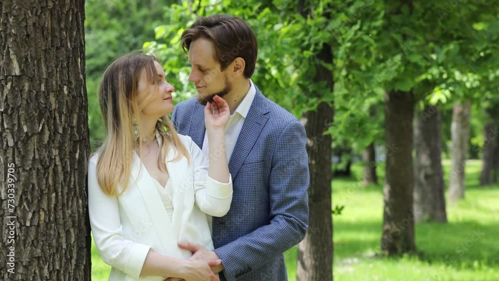 Happy pair caresses near tree in city garden at spring day, slow motion Happy pair caresses near tree in city garden at spring day, slow motion