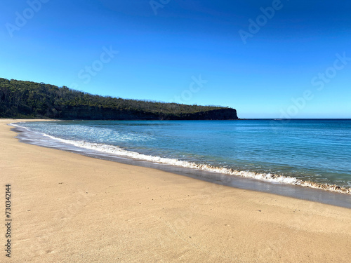 Island beach. View of bay  sand  waves and coastline. Landscape near the ocean with mountains.