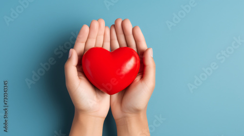 Hands holding a red heart on a color background with copy space. Top view, st Valentine day concept. Minimal abstract composition for 14 February celebration
