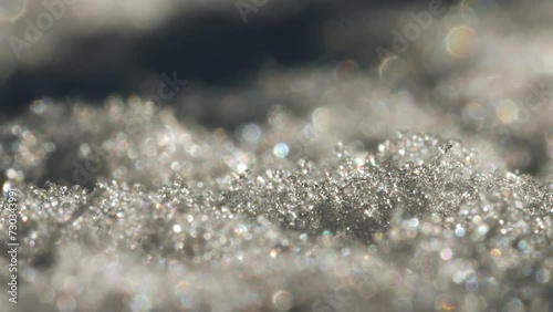 Close-up view of snow crystals that are glistening in the light. The focus is on photo