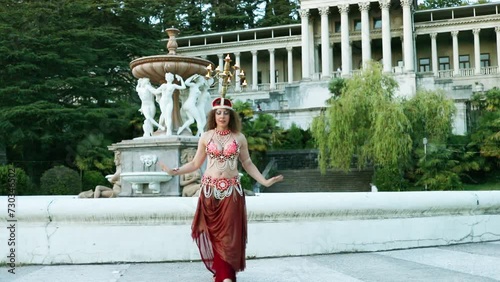 Woman dances belly dance with chandelier on head near fountain in Ordzhonikidze sanatorium, Sochi, Russia