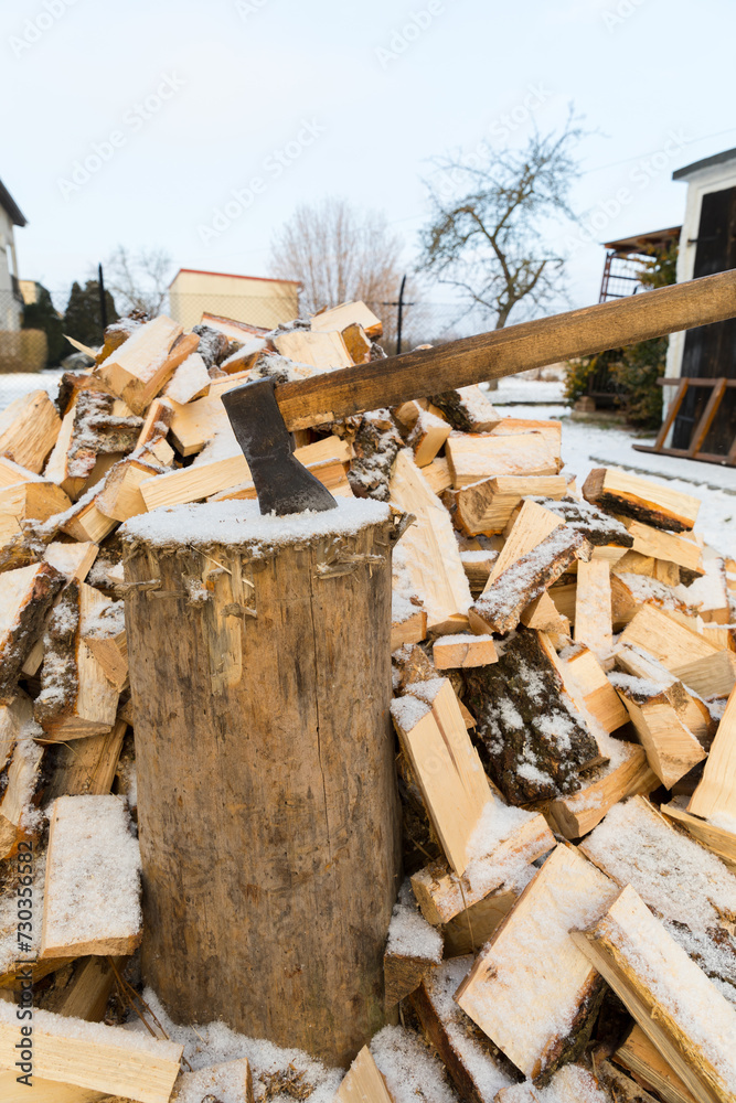 An ax for splitting firewood stuck into a stump for chopping wood. An ax for splitting firewood stuck into a stump for chopping wood.