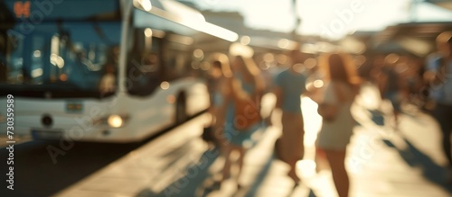 Blurred tourists standing in the background during summer, as buses are parked at a distance.