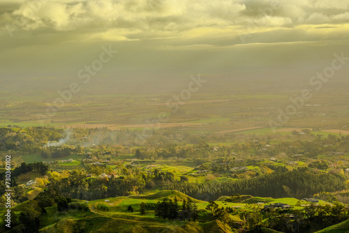Fototapeta Naklejka Na Ścianę i Meble -  Aerial View of Rolling Hills and Farmland Under Cloudy Sky - Morning Sunrise in New Zealand 