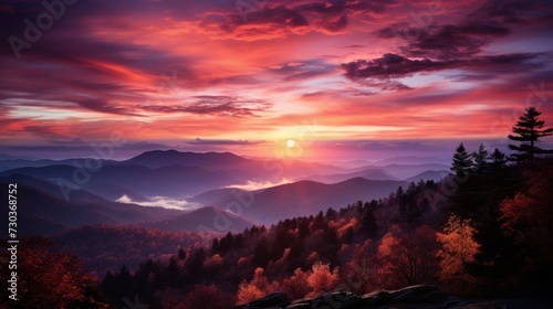 Dramatic sunrise over misty mountains with a spectrum of red and purple clouds
