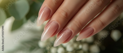 A woman's hand showcases her natural nails, highlighting their length and growth with a nail file.