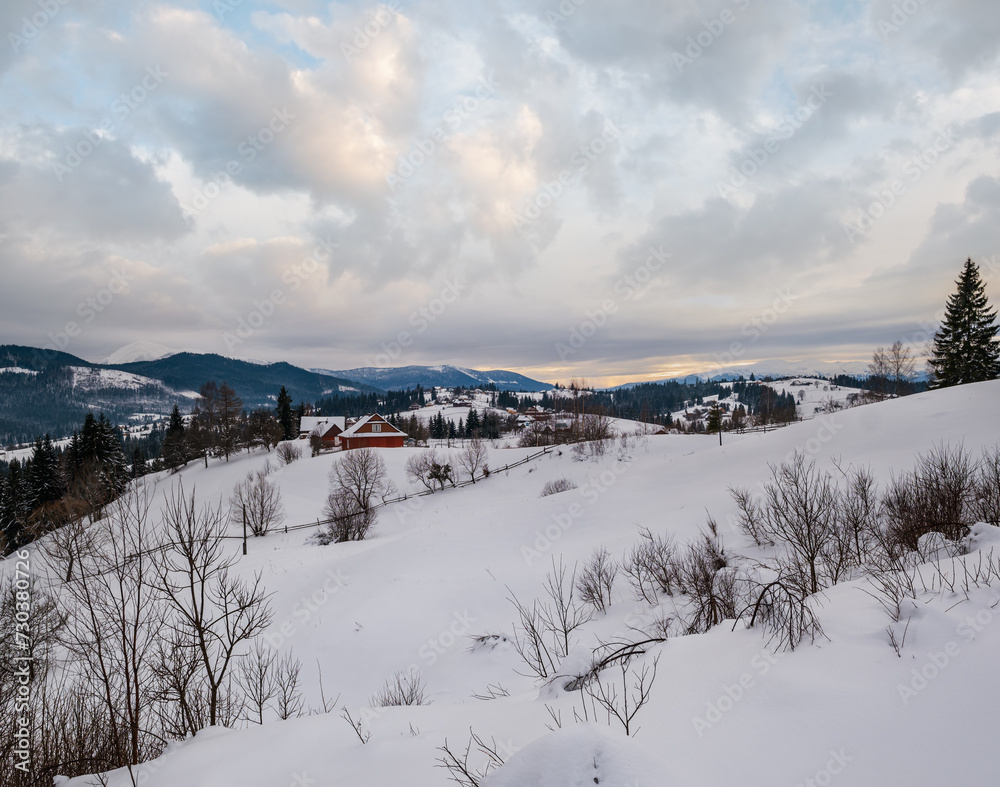 Small alpine village and winter snowy mountains in last sunset sunlight around, Voronenko, Carpathian, Ukraine.