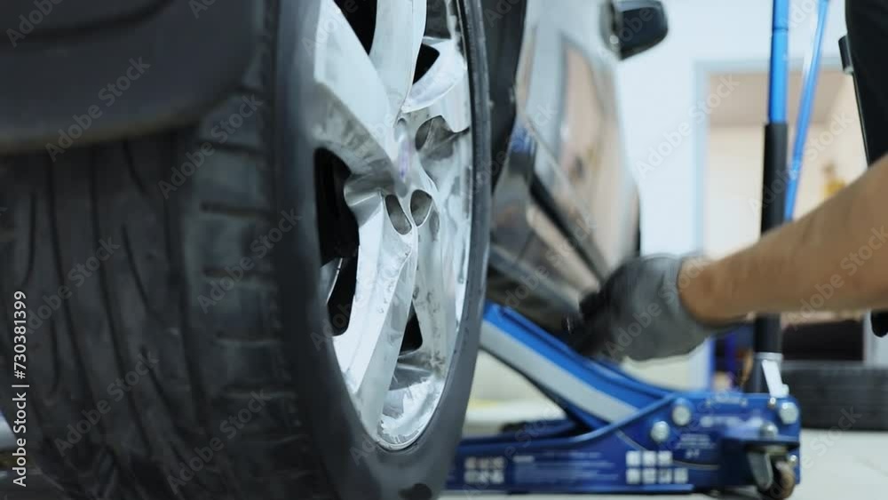 custom made wallpaper toronto digitalWorker tightens wheel of car which stand on lifting jack in service garage. Slow motion