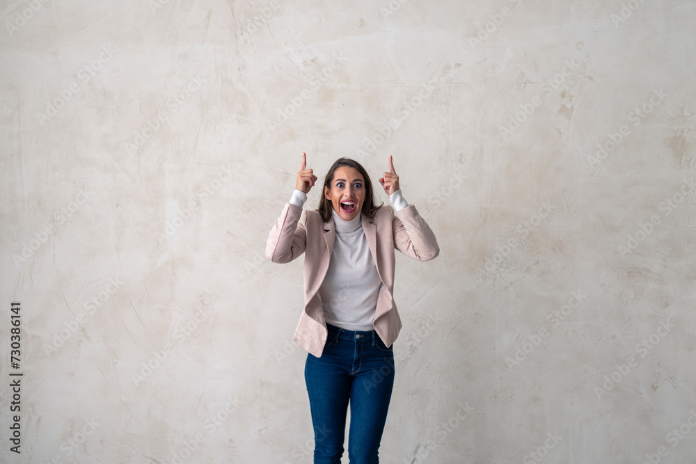 Studio shot of a excited young woman pointing towards copy space. Studio shot of a excited young woman pointing towards copy space.