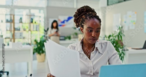 Woman, paperwork and laptop in office with reading for strategy, plan or review documents in rewind. Black person, concentrate and working for administration, analysis or record keeping in business photo