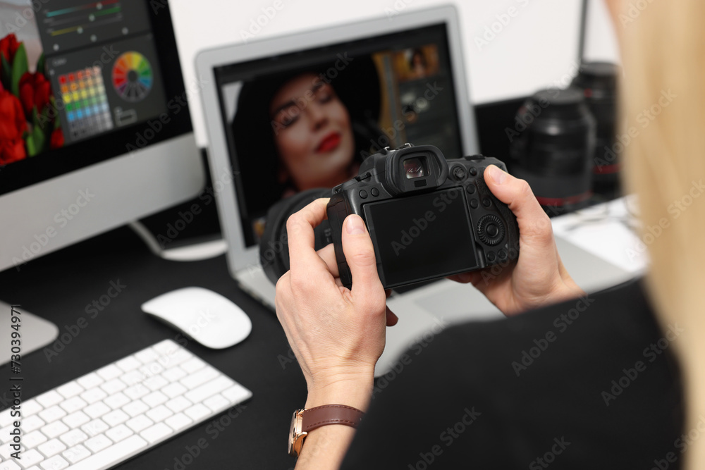 Professional photographer with digital camera at table indoors, closeup