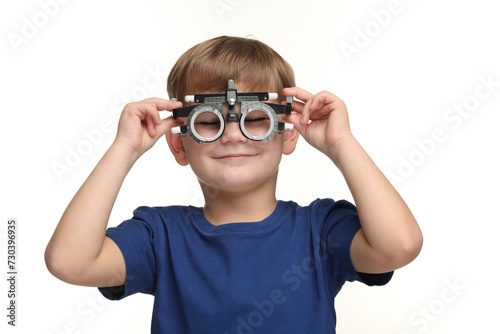 Vision testing. Little boy with trial frame on white background