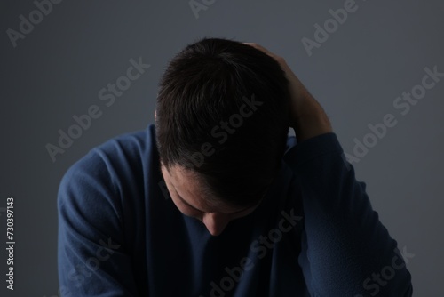 Sadness. Upset man on dark grey background © New Africa