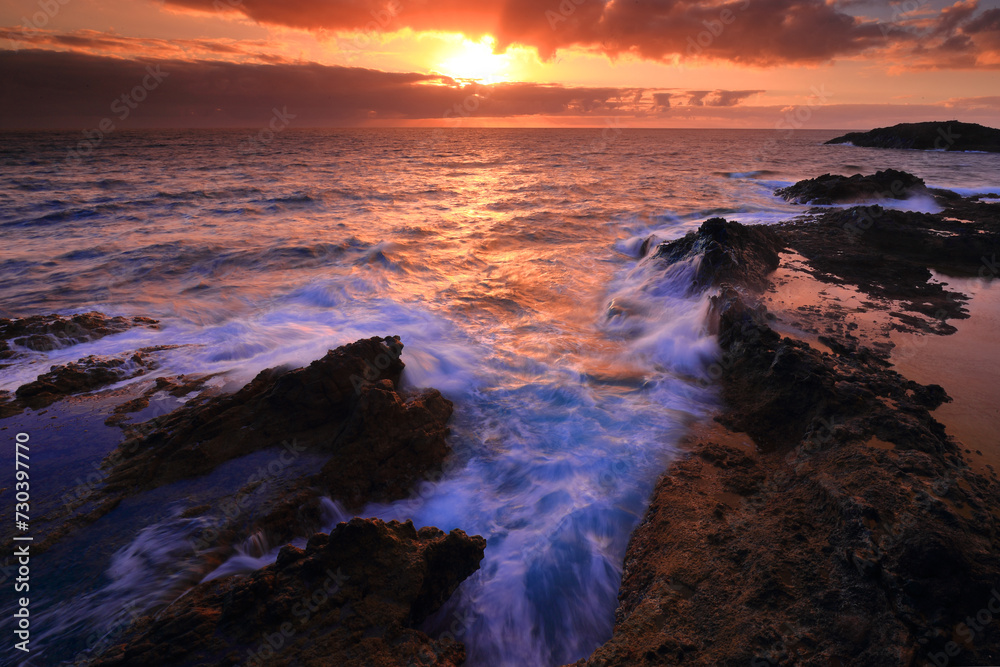 Sunset over rugged coastline with crashing waves Sunset over rugged coastline with crashing waves