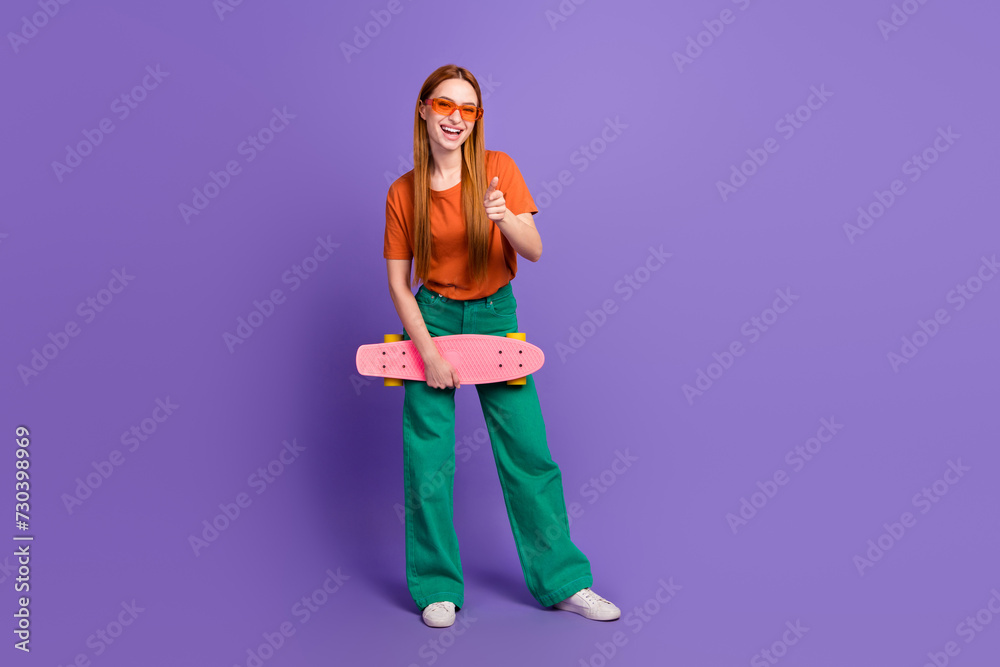 Photo of satisfied cheerful funky girl wear trendy clothes hold skate thumb up nice summer vacation isolated on purple color background Photo of satisfied cheerful funky girl wear trendy clothes hold skate thumb up nice summer vacation isolated on purple color background